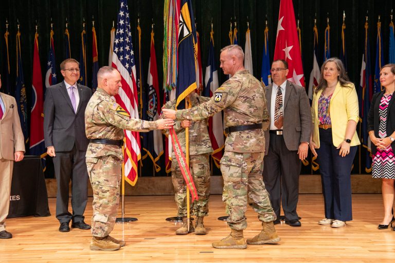 Two Army generals affix the Superior Unit Award streamer to the DEVCOM colors.